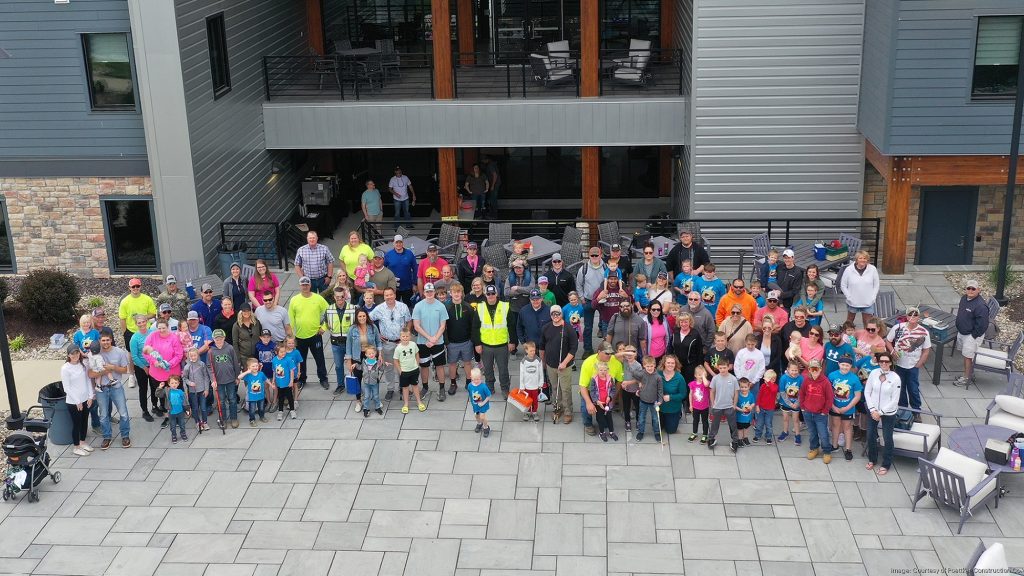 a large group of adults and children standing in front of a two-story gray building