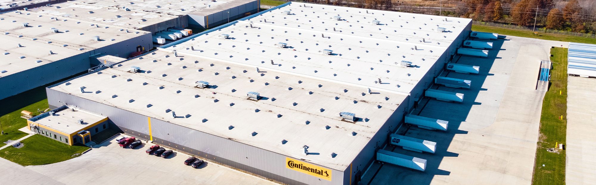 CTtA North Warehouse_Website Hero_2000x621 Aerial view of a white warehouse with trailers parked next to it