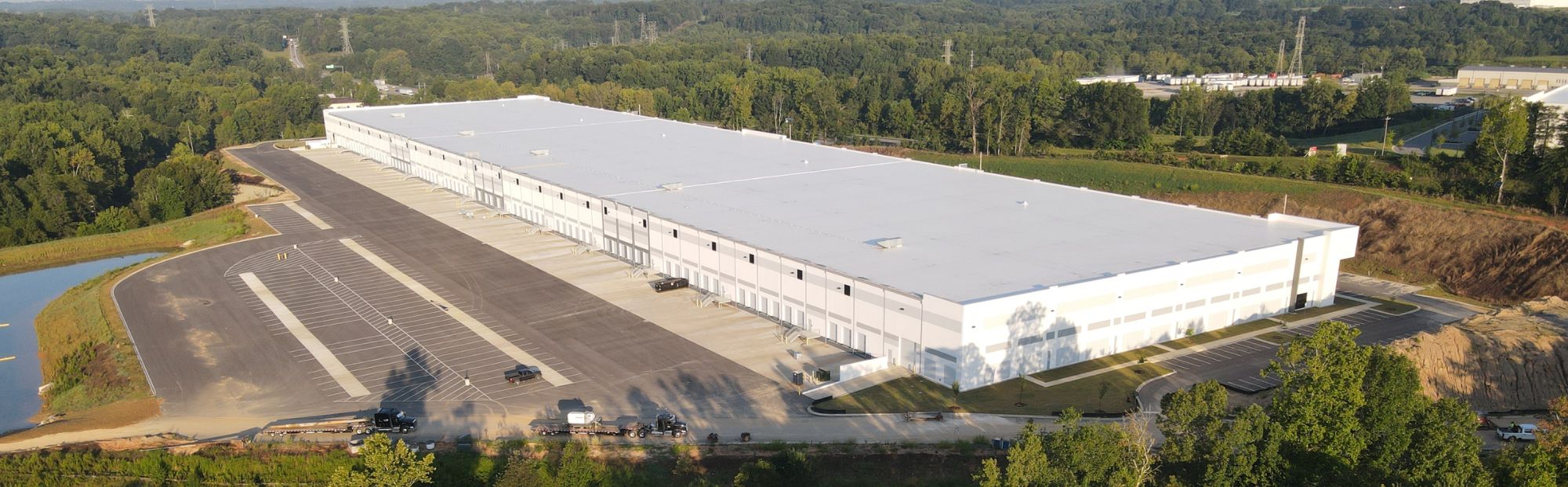 Gaston Commerce_Website Hero_2000x621 Aerial view of a distribution center with a white roof and a parking lot to the left