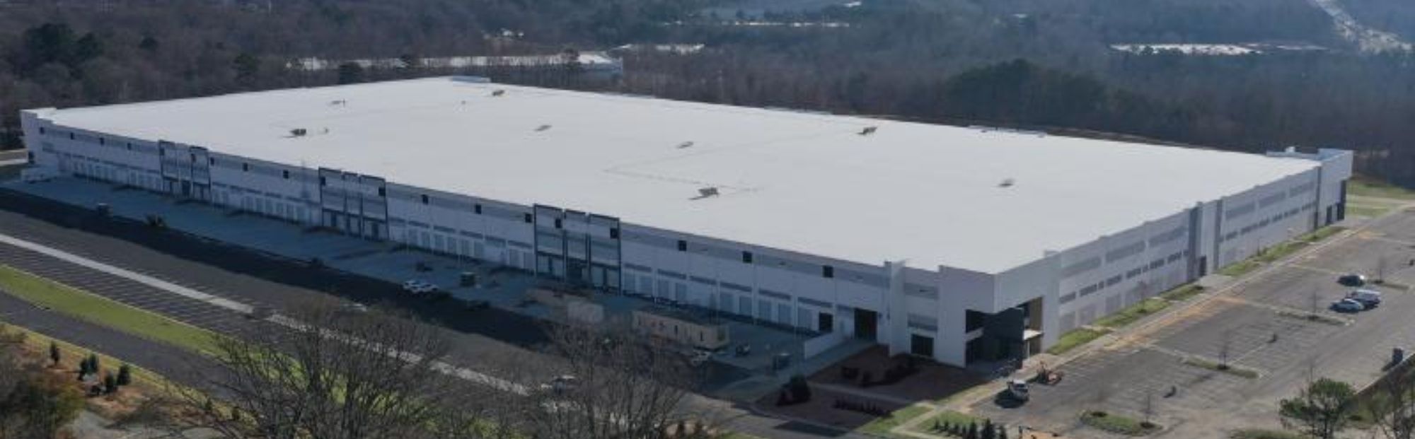 Oaks Logistics_Website Hero_2000x621 Aerial view of a large white distribution center