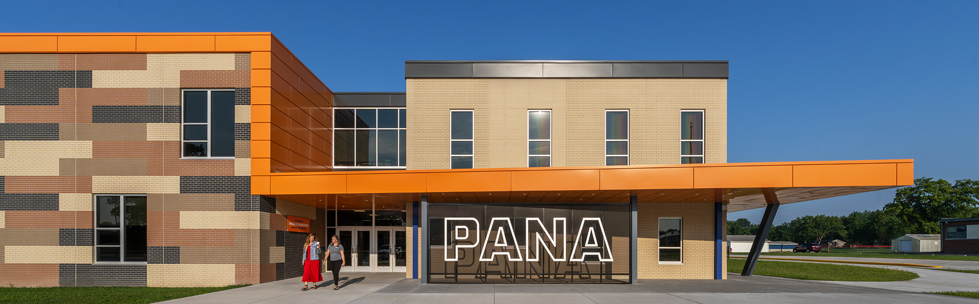 Pana ES_100_Exterior Front 3830A-2000×621 Exterior of a school with colored concrete