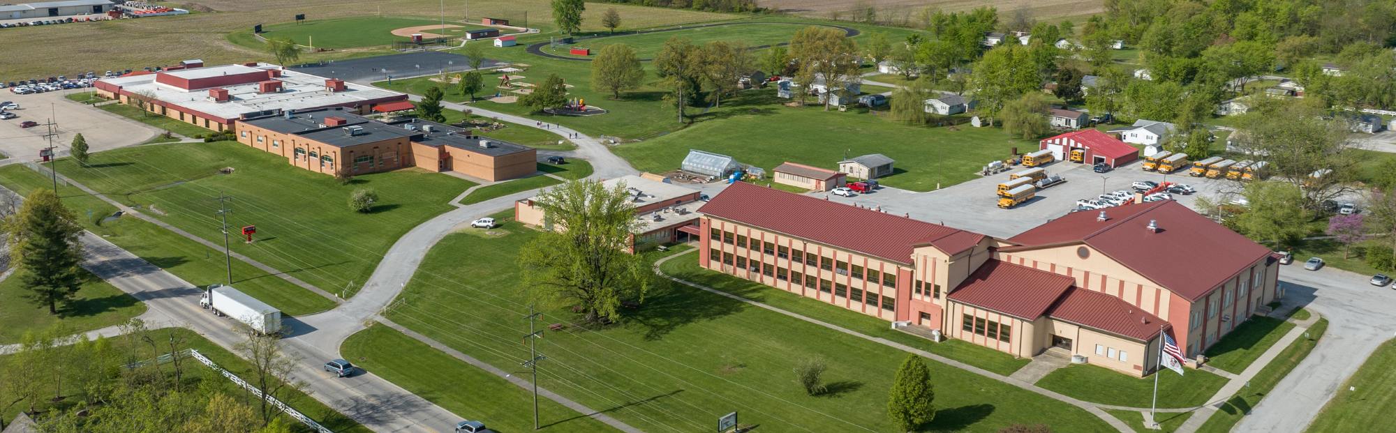North Clay HS Add & Reno_Website Hero_2000x621 Birds-eye view of a large school campus with green grass and dotted with trees