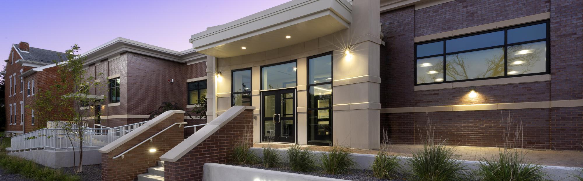 SIUE Advanced Care Clinic_Website Hero_2000x621 Red and tan brick building at dusk