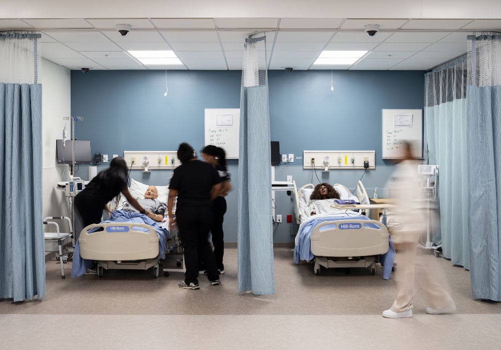 two hospital beds showing nursing students assisting a patient