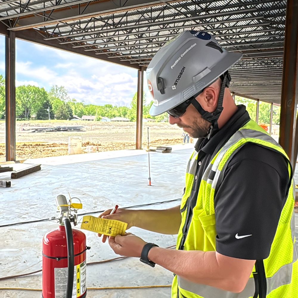 Safety_Body_Cahokia A man in a construction uniform inspects a fire extinguisher tag
