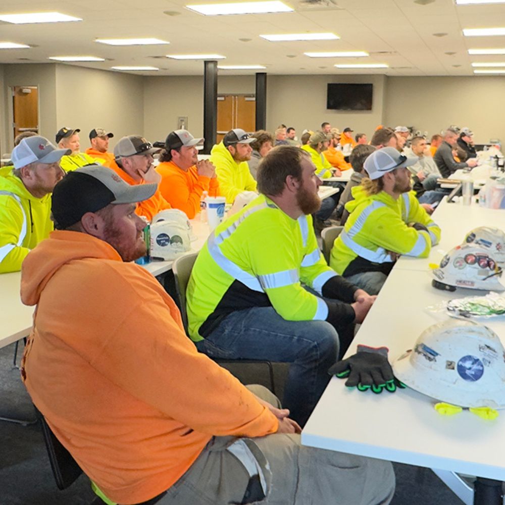Safety_Body_Safety Meeting Rows of men in orange and yellow shirts attend a meeting