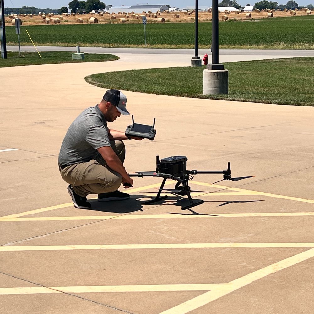 Technology_Body_Logan Drone A man squatting next to a large black drone