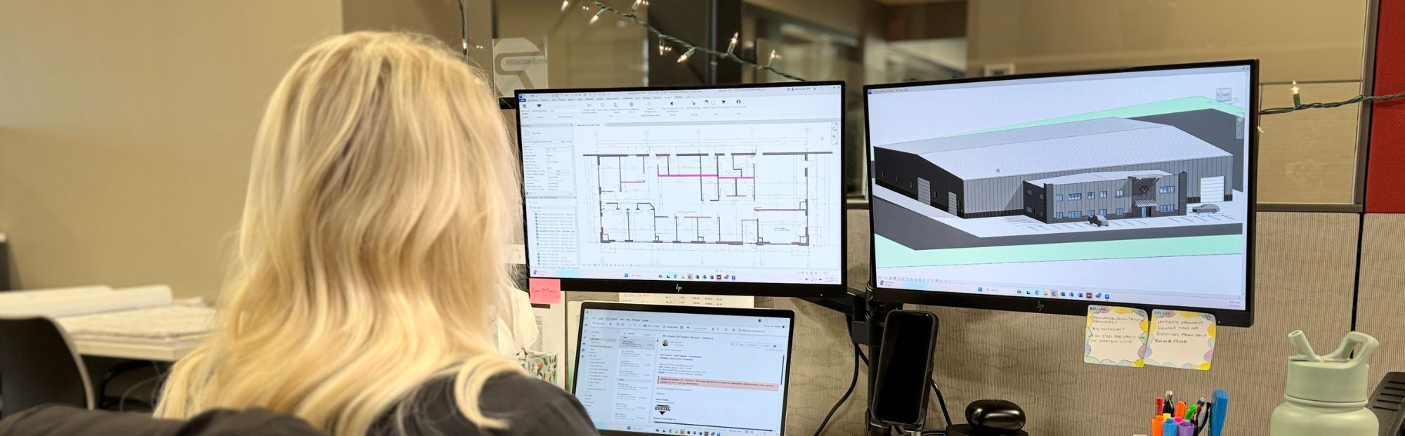 A blond woman looking at computer monitors