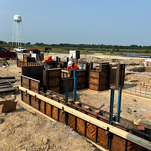 Two construction workers prepare for the footings of a new building