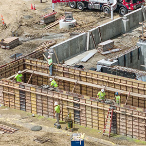 Construction workers wearing high-visibility shirts construct a building