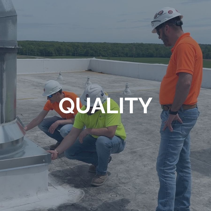Two construction workers inspecting a large pipe on the roof while another employee watches