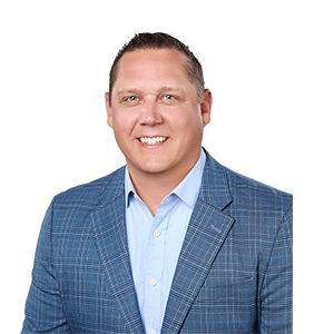 A smiling man with blue eyes, blue collared shirt, and a blue plaid sports coat
