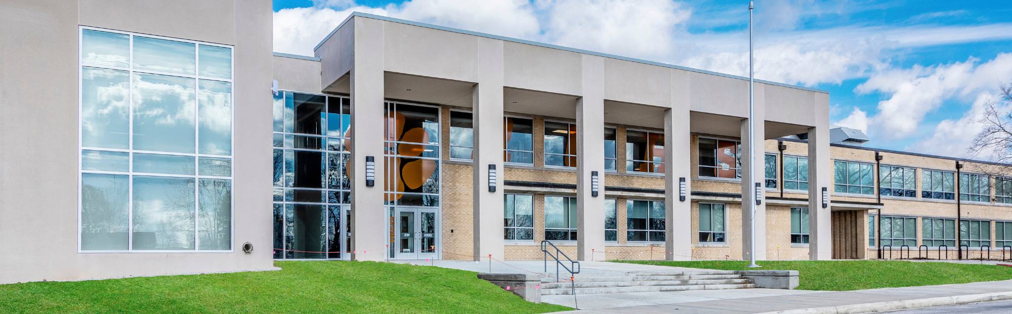 long tan building exterior with concrete pillars and floor to ceiling windows