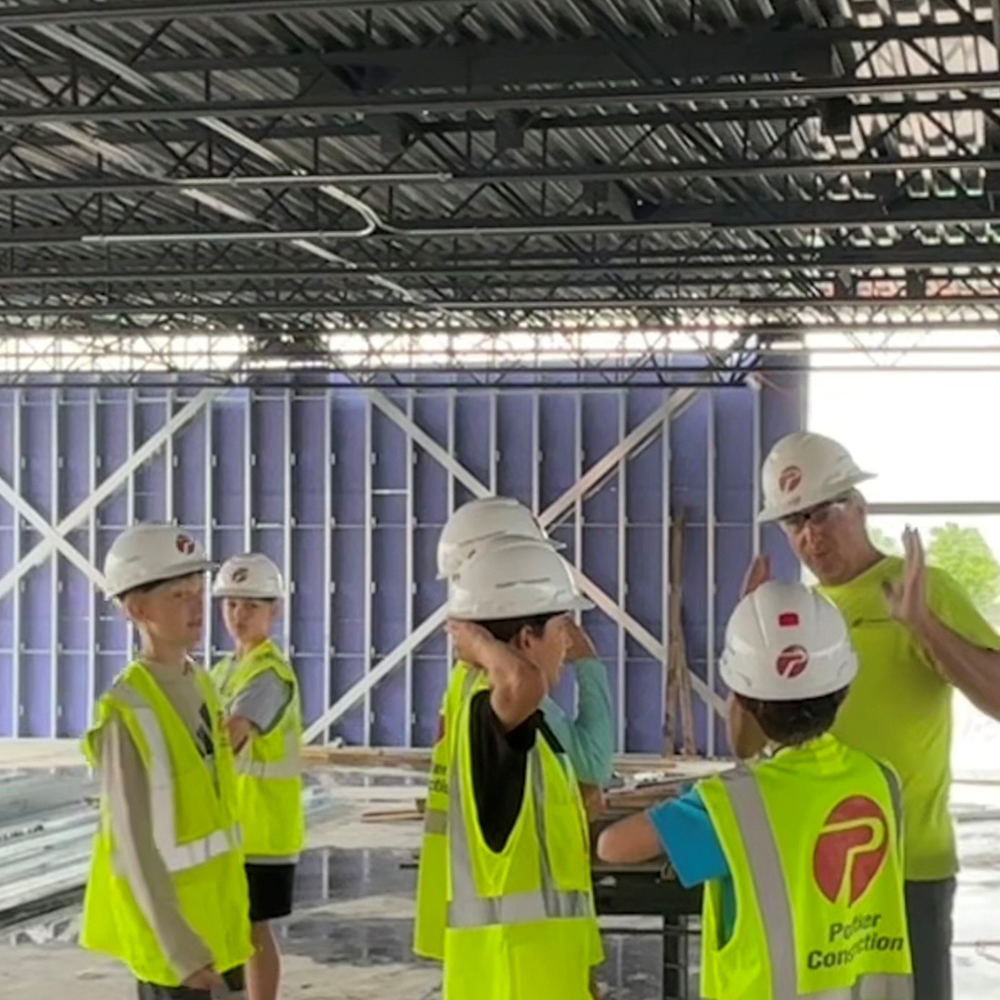 Elementary students in hard hats and high visibility vests