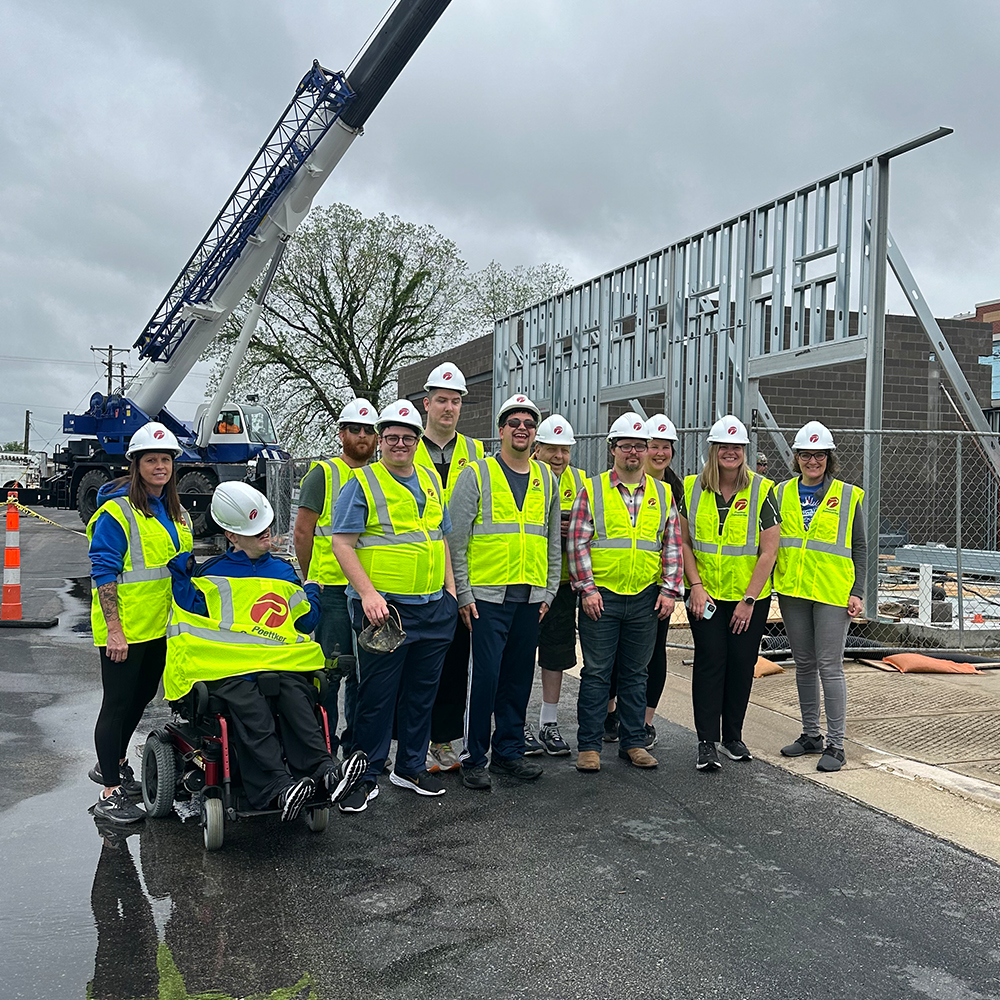 A group of men and women in hard hats and high-visibility vests face the camera