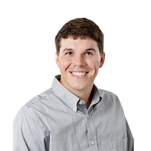 A grinning man with dark brown hair and a gray shirt