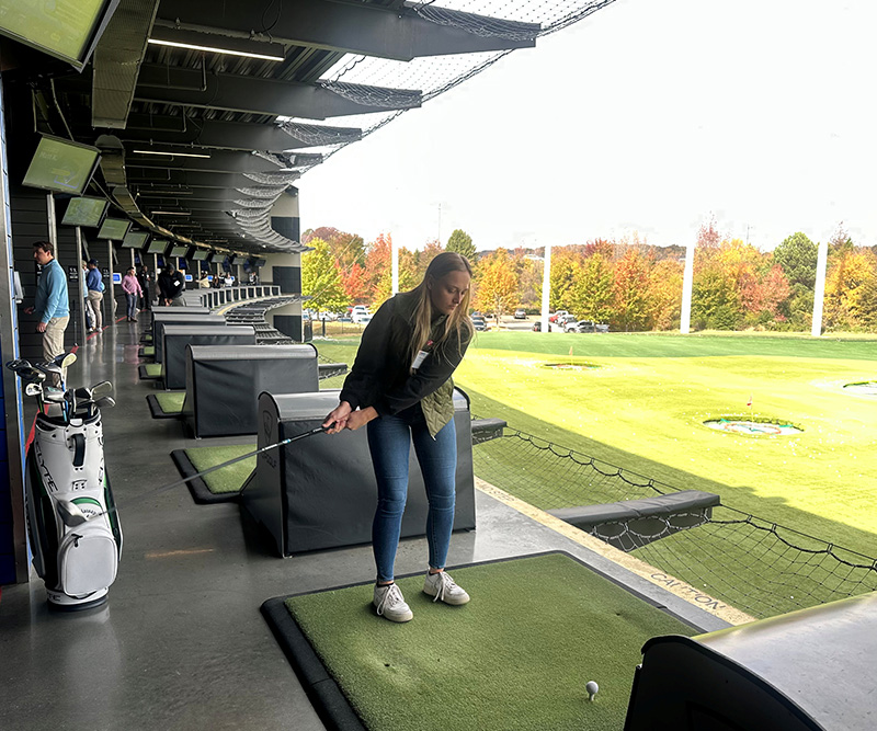 A woman is mid-swing at a Top Golf