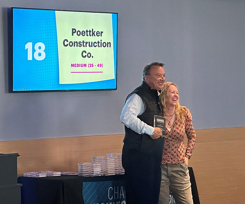 A man holds a glass award in one hand and gives a hug with the other