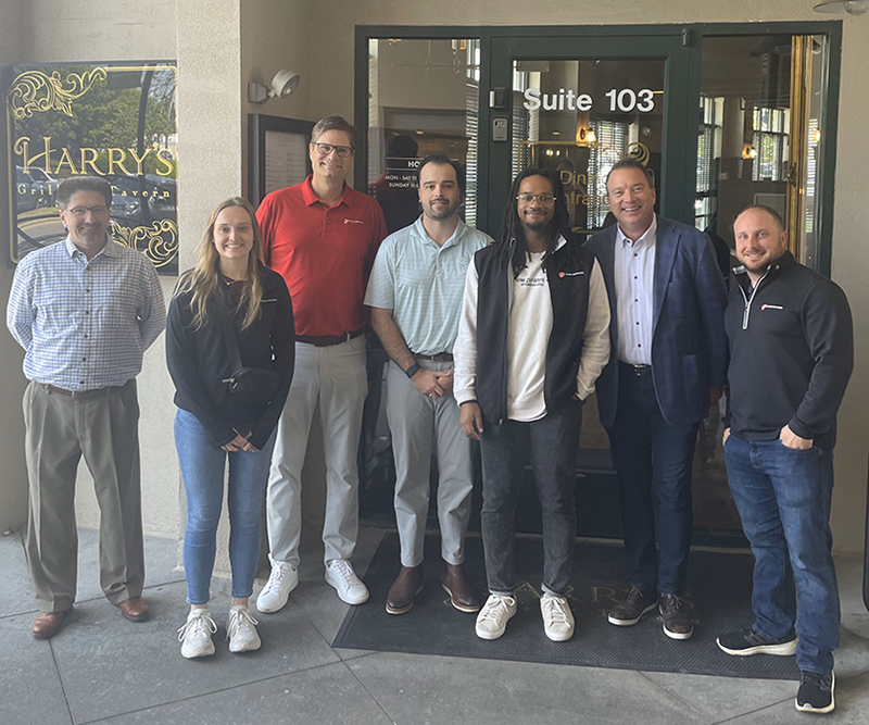 Six men and one woman stand outside a restaurant