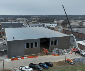 A crane next to a large concrete gym under construction 
