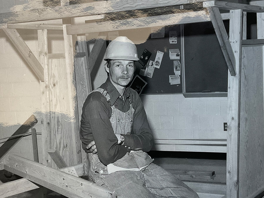 Black-and-white photo of a man in overalls and a hard hat