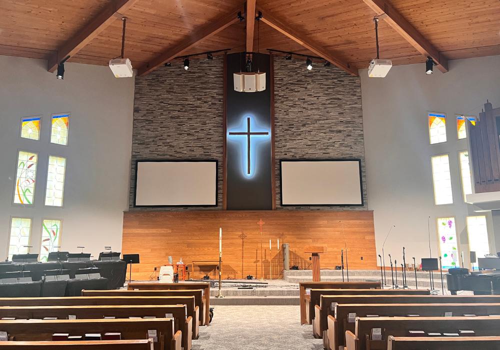 church interior with pews, music stands, and a large cross
