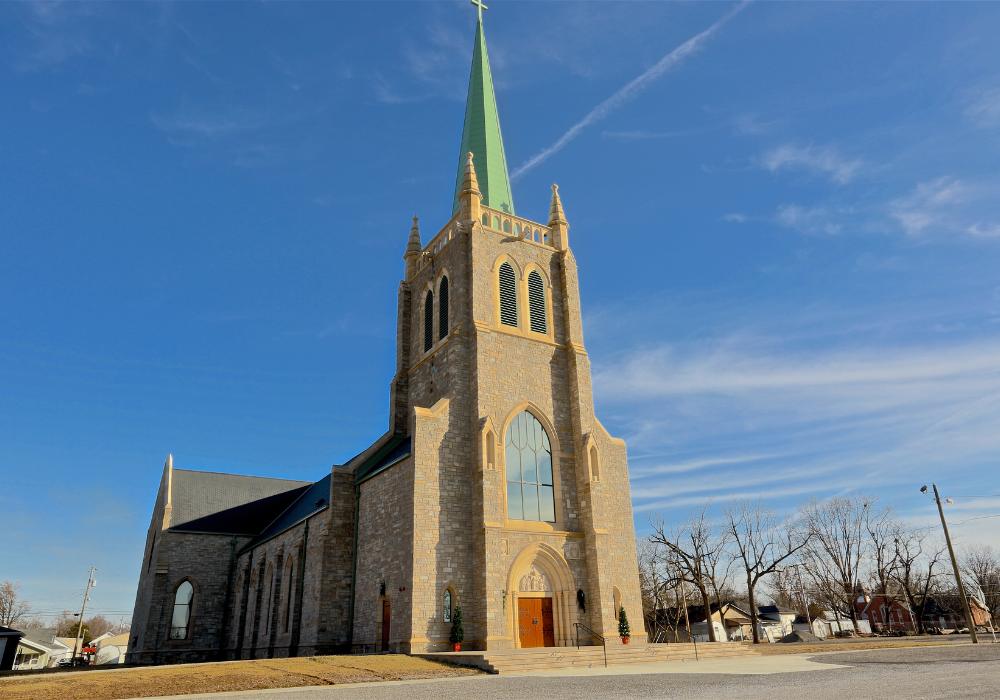 exterior of a church with light tan brick, tall steeple