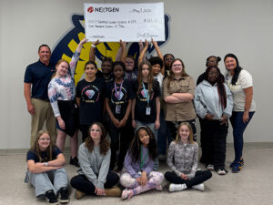 A group of female students holds an oversized check over their heads