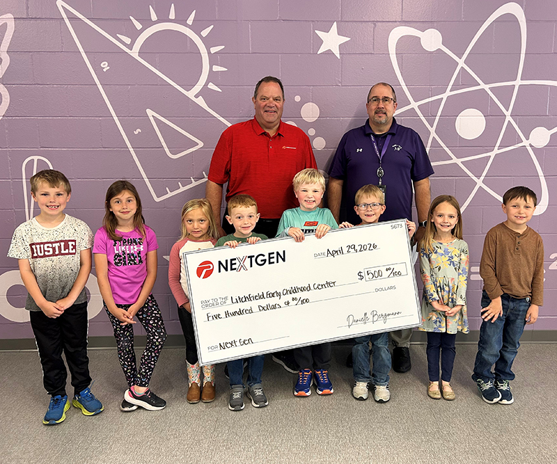 Two men stand behind eight children holding an oversized check