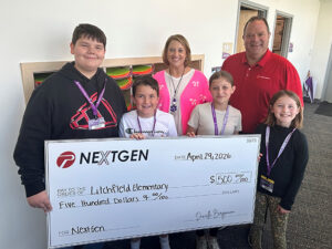 Four students hold an oversized check next to a woman and a man