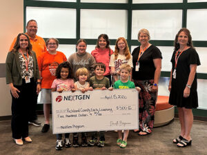 Students surrounded by teachers display a large check