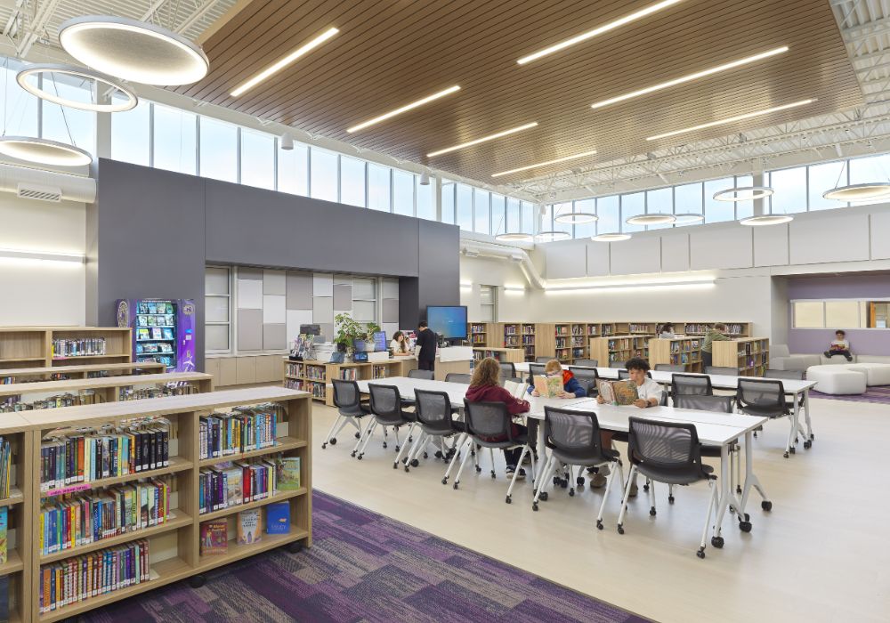 middle school library full of books and students reading at a table