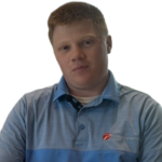 A man with red hair and a blue collared shirt tilts his head