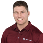 A smiling man with short brown hair wearing a maroon shirt