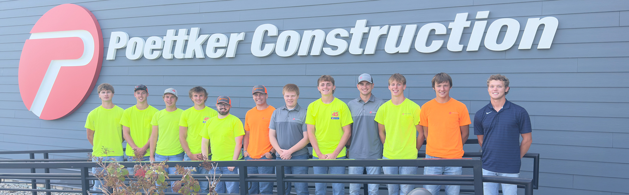 Intern-Webpage-Hero-2000×621 A group of men standing in front of a Poettker Construction sign