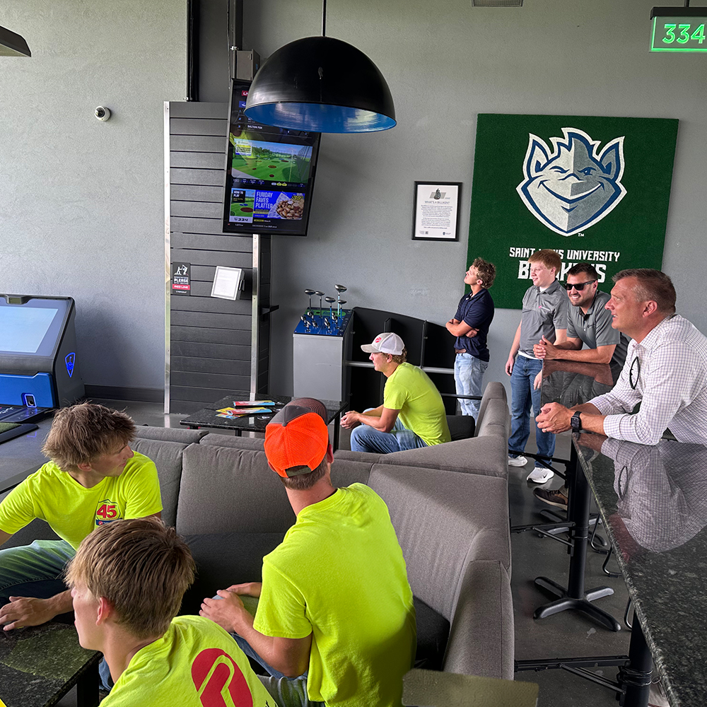 Men sit in a booth at a driving range