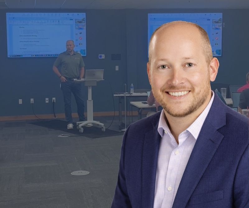 A smiling bald man in a blue sports coat