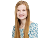 A smiling woman with long, strawberry-blonde hair, a necklace and a flowered shirt